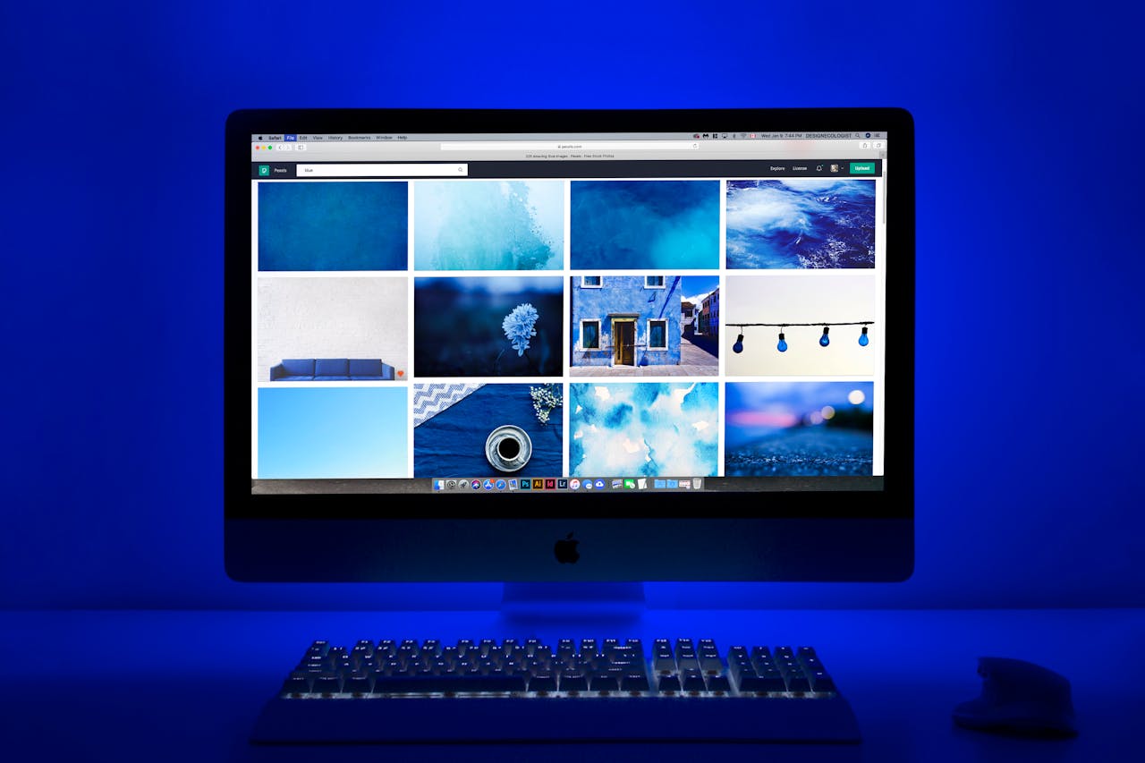 Modern workspace with a glowing blue theme and a computer monitor showcasing a gallery of images.